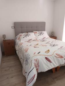- une chambre dotée d'un lit avec un couvre-lit floral dans l'établissement Grato y nuevo departamento, à Quilpué