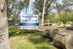 a sign for a park with birds standing next to a tree at Bright Cabin Park in Bright