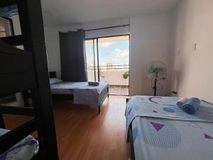 a room with two beds and a window with a balcony at Epifania Hostel in Cali
