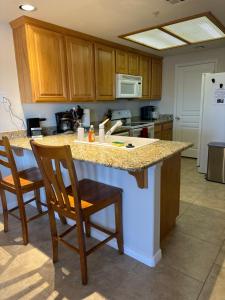 a kitchen with a counter with chairs and a refrigerator at Golfers Getaway - Mesquite in Mesquite