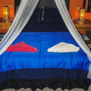 ein blaues Bett in einem Zelt mit zwei Kissen in der Unterkunft Suítes Cocaia in Ilhabela