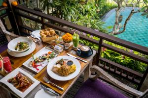 a table with plates of food on a balcony at Pramana Watu Kurung in Ubud