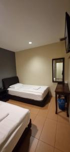 1 dormitorio con 2 camas, mesa y espejo en Tas Sakura Budget Hotel, en Kampong Baharu