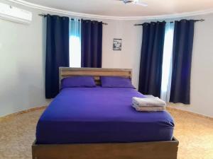 a bedroom with a bed with purple sheets and blue curtains at Riverside Lodge 