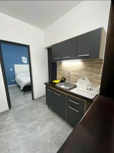 a kitchen with a sink and a room with a bed at Casita de encantó en Colonia in Colonia del Sacramento