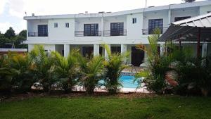 um edifício com piscina e palmeiras em frente em MARANATHA GUEST HOUSE 