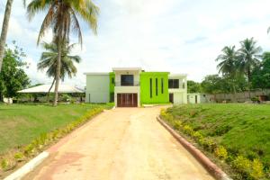 uma casa com uma porta verde numa estrada de terra em MARANATHA GUEST HOUSE 