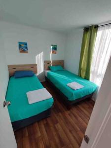 duas camas num pequeno quarto com lençóis verdes em Departamento nuevo sector sur entregado el 2022 em Antofagasta