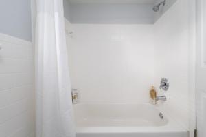 a bathroom with a shower and a white tub at Be A Nomad Beachside Apartments in Jacksonville Beach