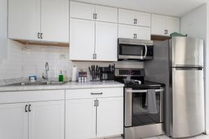 cocina con armarios blancos y nevera de acero inoxidable en Be A Nomad Beachside Apartments en Jacksonville Beach