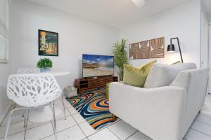a living room with a white couch and a tv at Be A Nomad - Beachside Apartments in Jacksonville Beach +58 photos