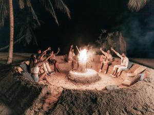 een groep mensen die rond een vuurplaats op het strand zitten bij Sun Siyam Pasikudah in Pasikuda