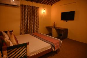 sypialnia z łóżkiem, biurkiem i telewizorem w obiekcie Gramya Resort w mieście Alwar