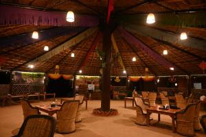 un restaurante con mesas y sillas y un árbol en el medio en Gramya Resort, en Alwar