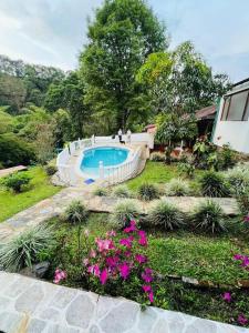 un jardín con piscina y algunas flores en Rincón del colibrí/casa campestre/piscina/la vega, en La Vega