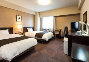 um quarto de hotel com duas camas e uma televisão de ecrã plano em Daiwa Roynet Hotel Mito em Mito
