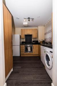 a kitchen with a refrigerator and a washer and dryer at Pristine Relocation Pamers Green in London