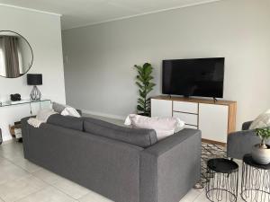 a living room with a gray couch and a flat screen tv at The Blyde Stylish Homes in Pretoria