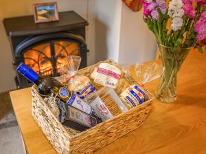 a basket of food and a bottle of wine on a table at Coachingmans Cottage in Trecastle