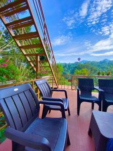 four chairs and a table on a deck with a view at Munnar BnB in Munnar