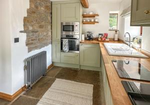 - une cuisine avec des placards verts et une cuisinière four supérieur dans l'établissement Red Squirrel Cottage, à Hawes