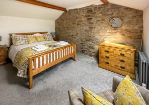 ein Schlafzimmer mit einem Bett und einer Steinmauer in der Unterkunft Red Squirrel Cottage in Hawes