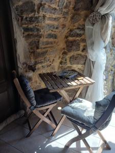 a table and chairs in front of a stone wall at Au coeur du Caylar in Le Caylar