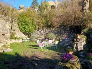 a garden with chairs and a table and a stone wall at Au coeur du Caylar in Le Caylar