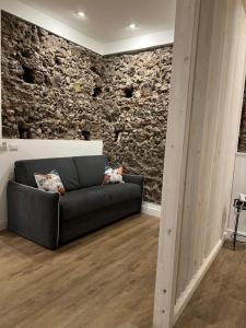 a living room with a couch in front of a stone wall at Bibike in Catania