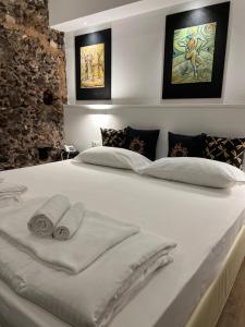 um quarto com uma cama branca e toalhas em Bibike em Catânia