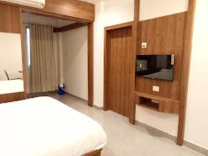 Schlafzimmer mit einem Bett und einem Flachbild-TV in der Unterkunft Hotel Grand Residency , Kolegaon in Dive