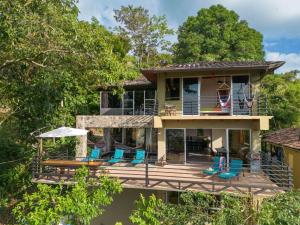 a house with a wrap around deck with chairs at Exclusive Villa Tanager Ocean View w AC Private pool terrace in Quepos