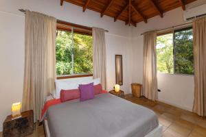a bedroom with a large bed in a room with windows at Exclusive Villa Tanager Ocean View w AC Private pool terrace in Quepos +34 photos