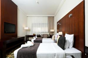 a hotel room with two beds and a television at Aavri Hotel in Dubai