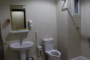 een badkamer met een wastafel, een toilet en een spiegel bij فندق ضيوف المقام للغرف والشقق المفروشة in Mekka