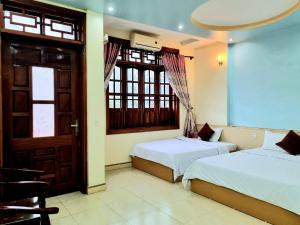 twee bedden in een kamer met een deur en ramen bij Ha Giang Donkey hostel in Ha Giang