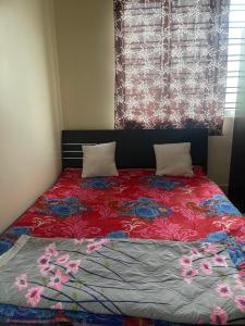 a bed with a red comforter and two pillows at Lakeview Apartments Homestay in Agartala