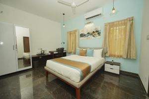 1 dormitorio con cama, escritorio y espejo en Bay Breeze Suites, en Chennai