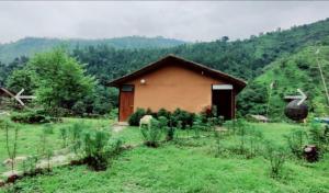 a house in a field with a horse in front of it at UPASANA THE RIVER SIDE RESORT in Marchula
