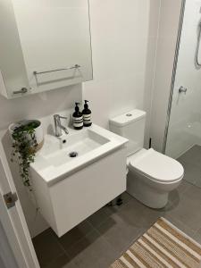 a white bathroom with a toilet and a sink at NEW BOUTIQUE 1bd Apt in Canberra