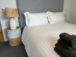 1 dormitorio con 1 cama blanca con lámpara y toallas en NEW BOUTIQUE 1bd Apt en Canberra