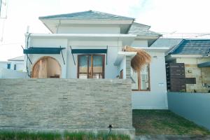 una casa blanca con una pared de piedra delante de ella en Felgio Villa Jimbaran en Ungasan