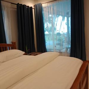 um quarto com 2 camas e uma janela em บ้านระเบียงเลหลังสวน ทั้งหลัง 2 นอน 2 น้ำ 1 ครัว em Ban Hin Sam Kon