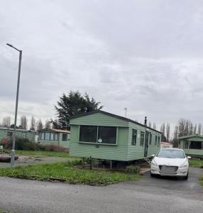 une petite maison verte dans un parking avec une voiture dans l'établissement BLW 04, à Great Billing