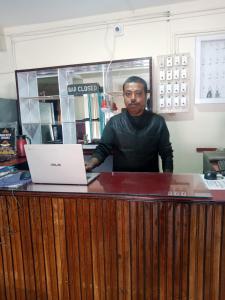 a man standing behind a counter with a laptop at HOTEL TASHI NORLING Near Mall Road in Gangtok