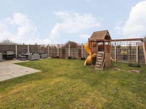 a small yard with a playground with a slide at The Hideaway Beach House in New Romney