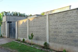 un mur en briques avec un portail et un garage dans l'établissement Tulivu homes, 