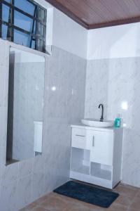 La salle de bains blanche est pourvue d'un lavabo et d'un miroir. dans l'établissement Tulivu homes, 
