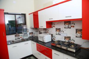 une cuisine avec des armoires rouges et blanches et un micro-ondes dans l'établissement Marari Lois Beach Homes, à Mararikulam 40 autres photos