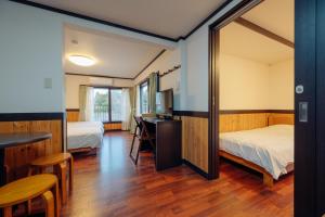 神戸市にあるホテル モルゲンロートのベッド2台、デスク、鏡が備わる客室です。